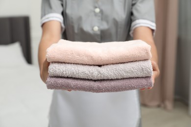 Photo of Chambermaid with stack of terry towels in hotel room, closeup