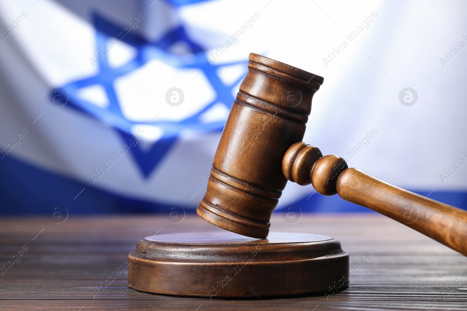 Photo of Judge's gavel on wooden table against flag of Israel, closeup