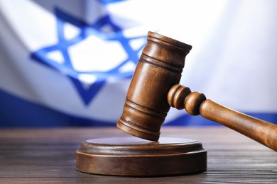 Photo of Judge's gavel on wooden table against flag of Israel, closeup