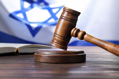 Photo of Judge's gavel and book on wooden table against flag of Israel, closeup