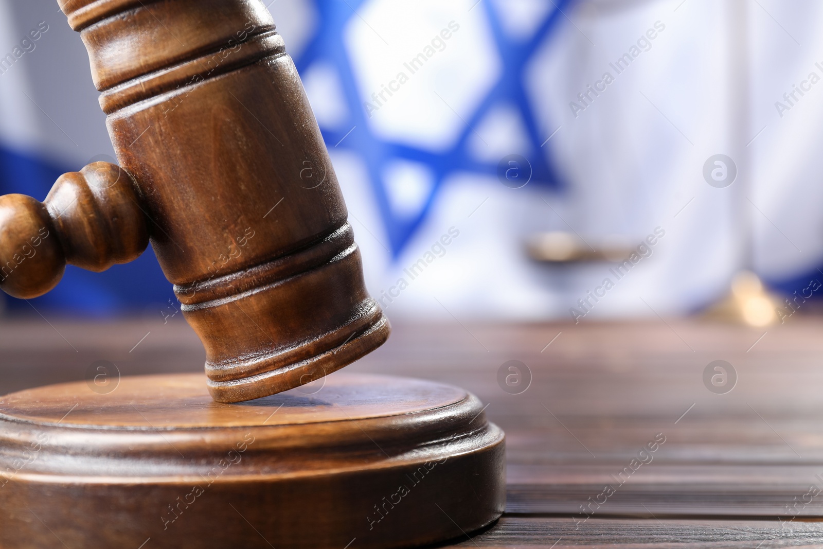 Photo of Judge's gavel on wooden table against flag of Israel, closeup. Space for text