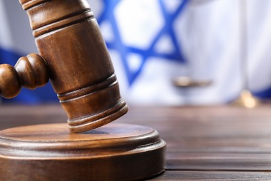 Photo of Judge's gavel on wooden table against flag of Israel, closeup. Space for text