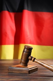 Photo of Judge's gavel on wooden table against flag of Germany, closeup