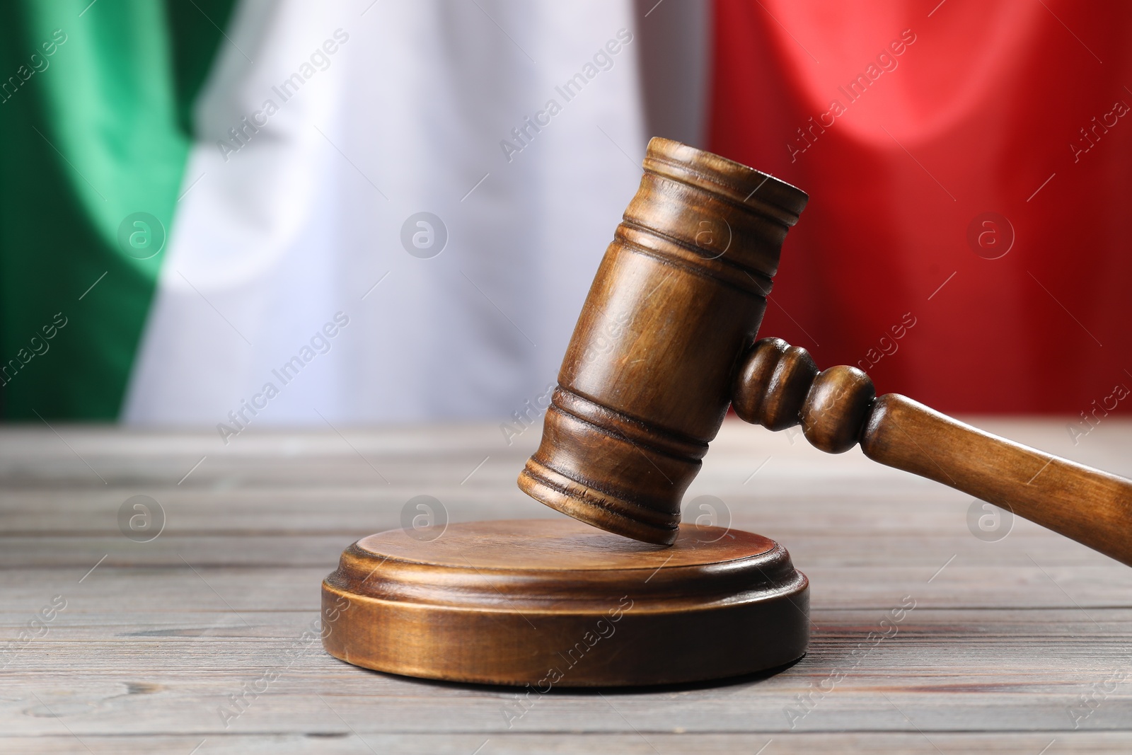 Photo of Judge's gavel on wooden table against flag of Italy, closeup