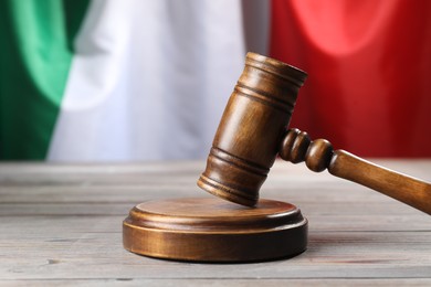 Photo of Judge's gavel on wooden table against flag of Italy, closeup
