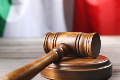 Photo of Judge's gavel on wooden table against flag of Italy, closeup