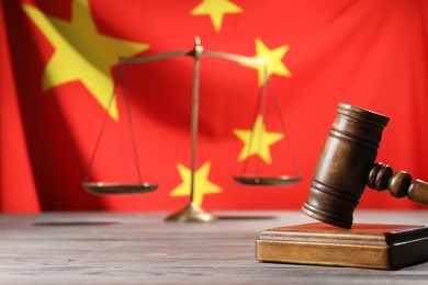 Photo of Judge's gavel and scales on wooden table against flag of China, closeup. Space for text