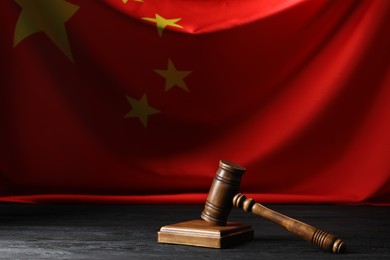 Photo of Judge's gavel on black wooden table against flag of China, space for text