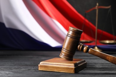 Photo of Judge's gavel, flag of France and scales on black wooden table, closeup. Space for text
