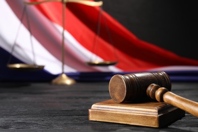 Photo of Judge's gavel, flag of France and scales on black wooden table, closeup. Space for text