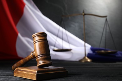 Photo of Judge's gavel, flag of France and scales on black wooden table, closeup