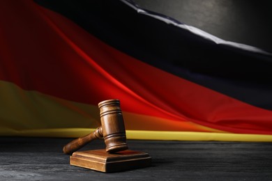 Photo of Judge's gavel on black wooden table against flag of Germany
