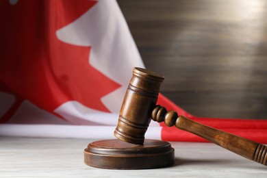 Photo of Judge's gavel on wooden table against flag of Canada, closeup