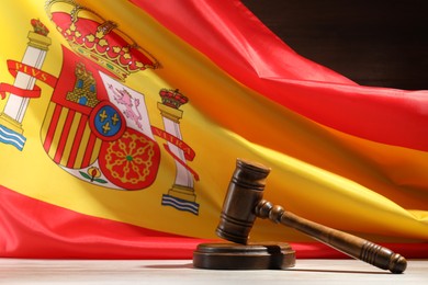 Photo of Judge's gavel on wooden table against flag of Spain