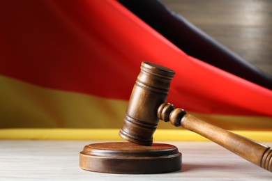Photo of Judge's gavel on wooden table against flag of Germany, closeup