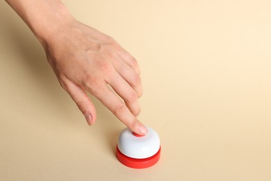 Photo of Woman pressing red button on beige background, closeup