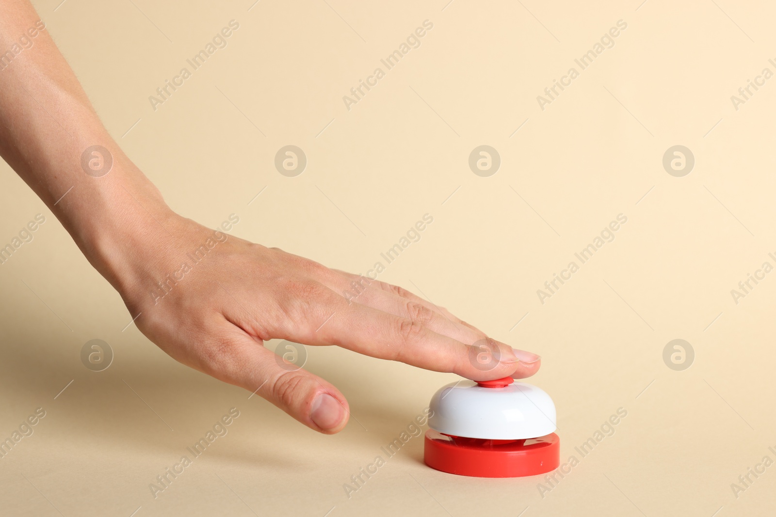 Photo of Woman pressing red button on beige background, closeup