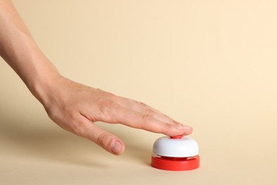 Photo of Woman pressing red button on beige background, closeup