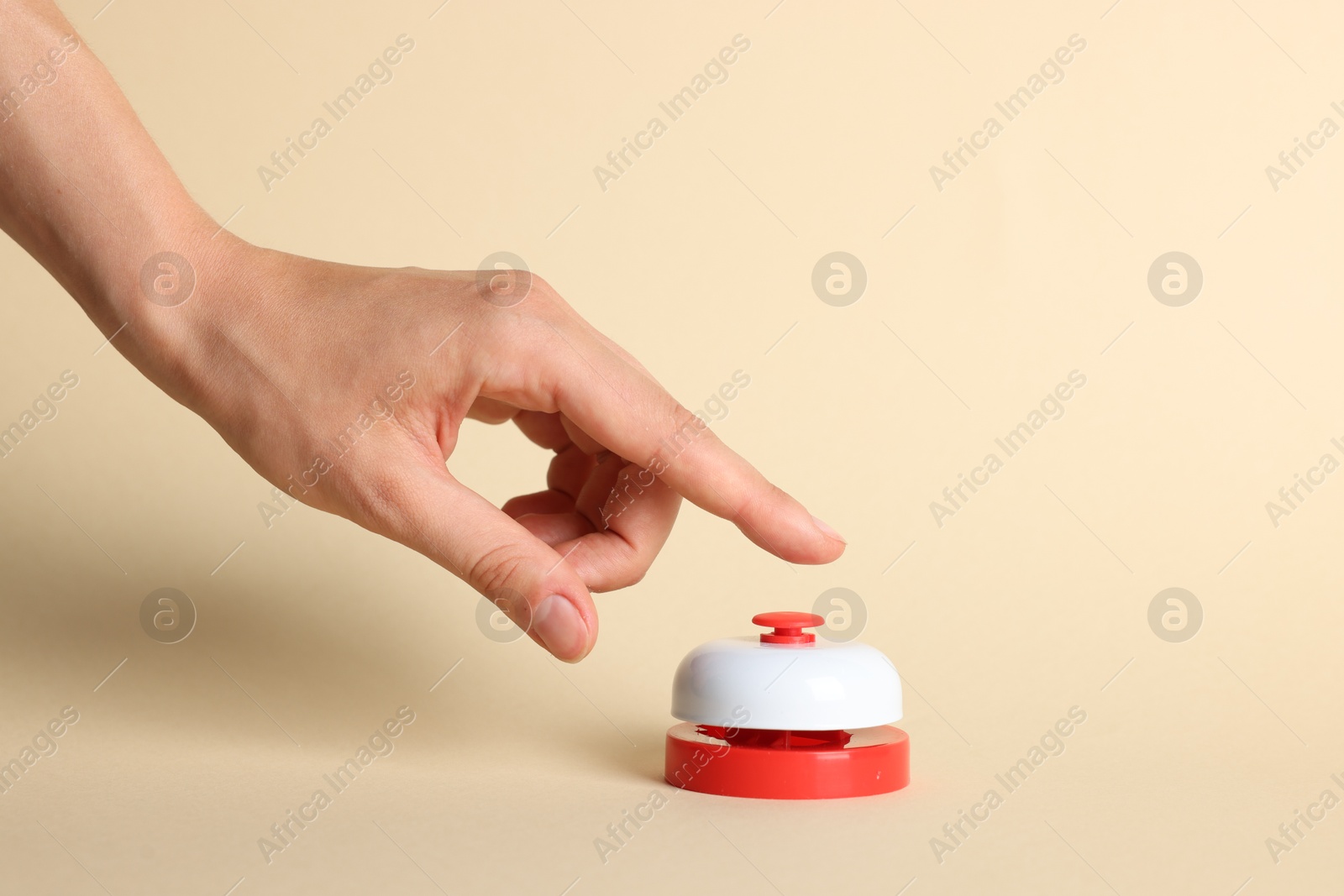 Photo of Woman pressing red button on beige background, closeup
