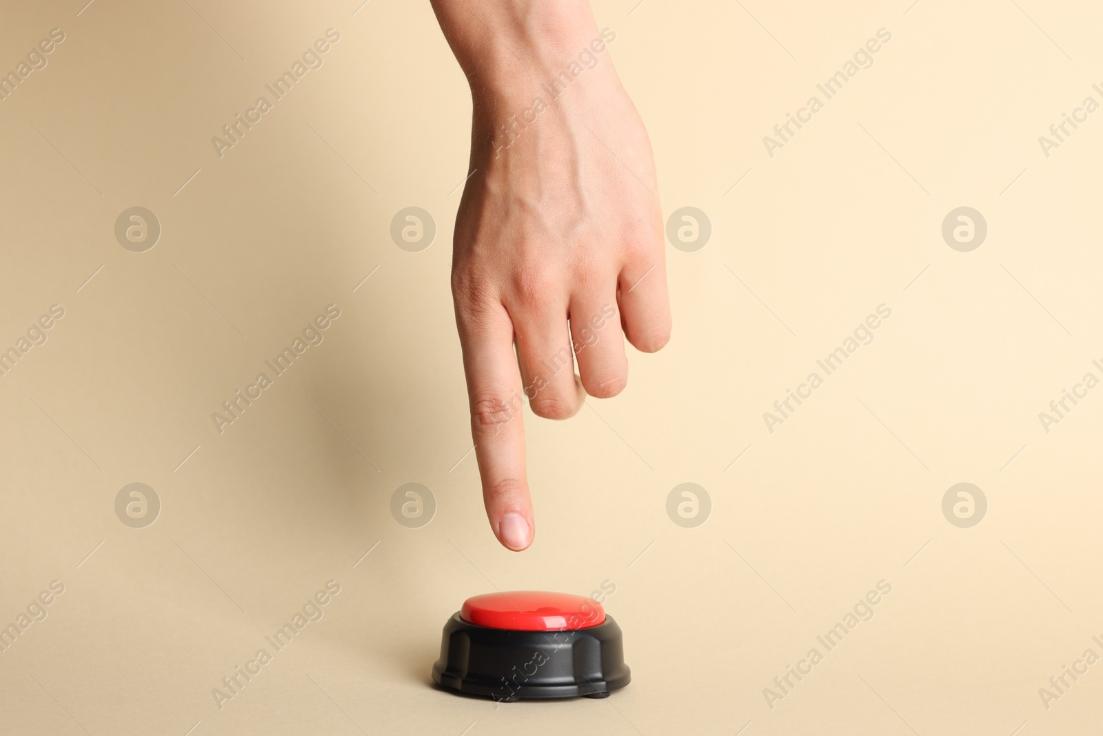 Photo of Woman pressing red button on beige background, closeup
