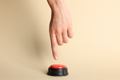 Photo of Woman pressing red button on beige background, closeup