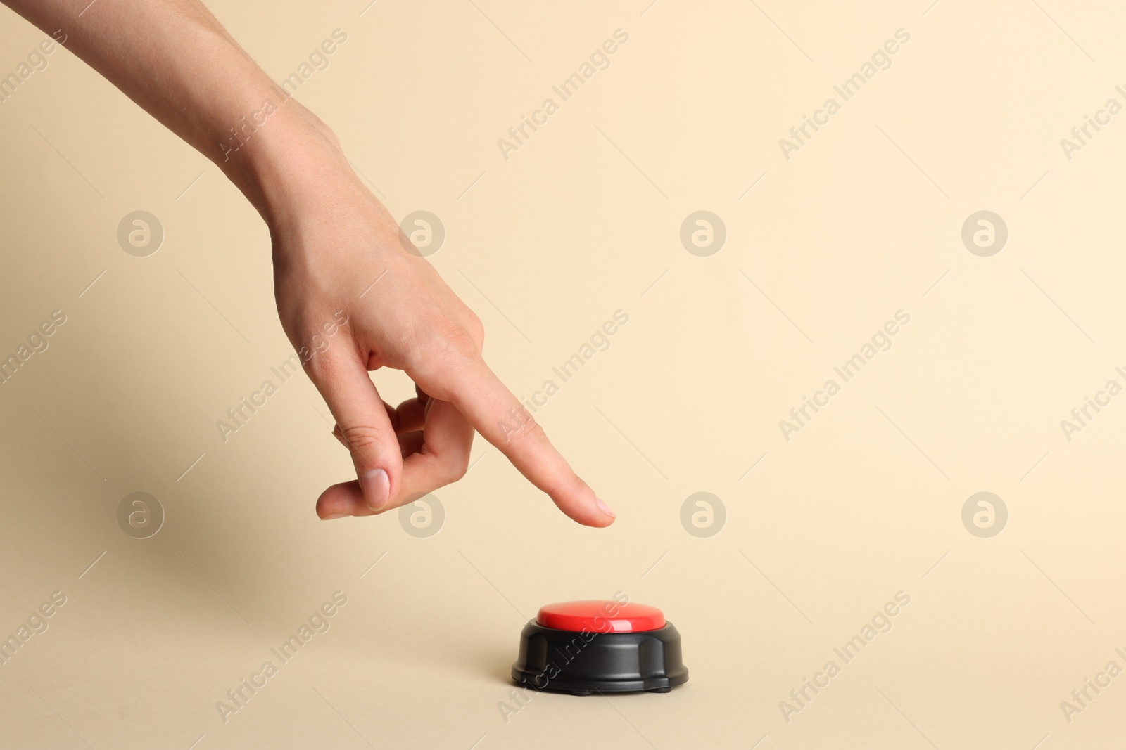 Photo of Woman pressing red button on beige background, closeup