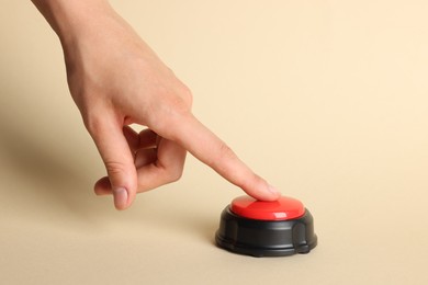 Photo of Woman pressing red button on beige background, closeup