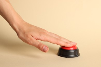 Photo of Woman pressing red button on beige background, closeup