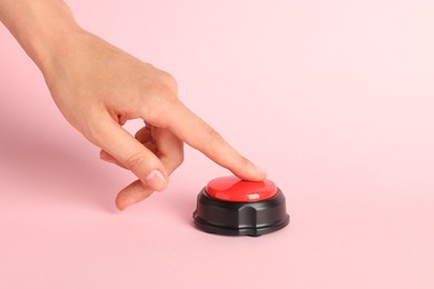 Photo of Woman pressing red button on pink background, closeup
