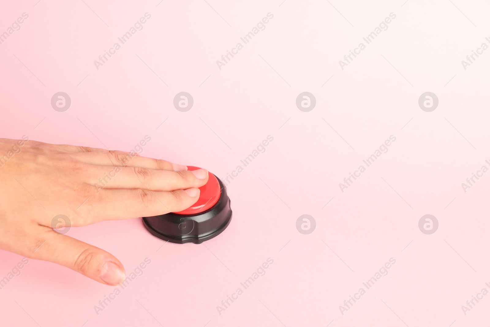 Photo of Woman pressing red button on pink background, closeup. Space for text
