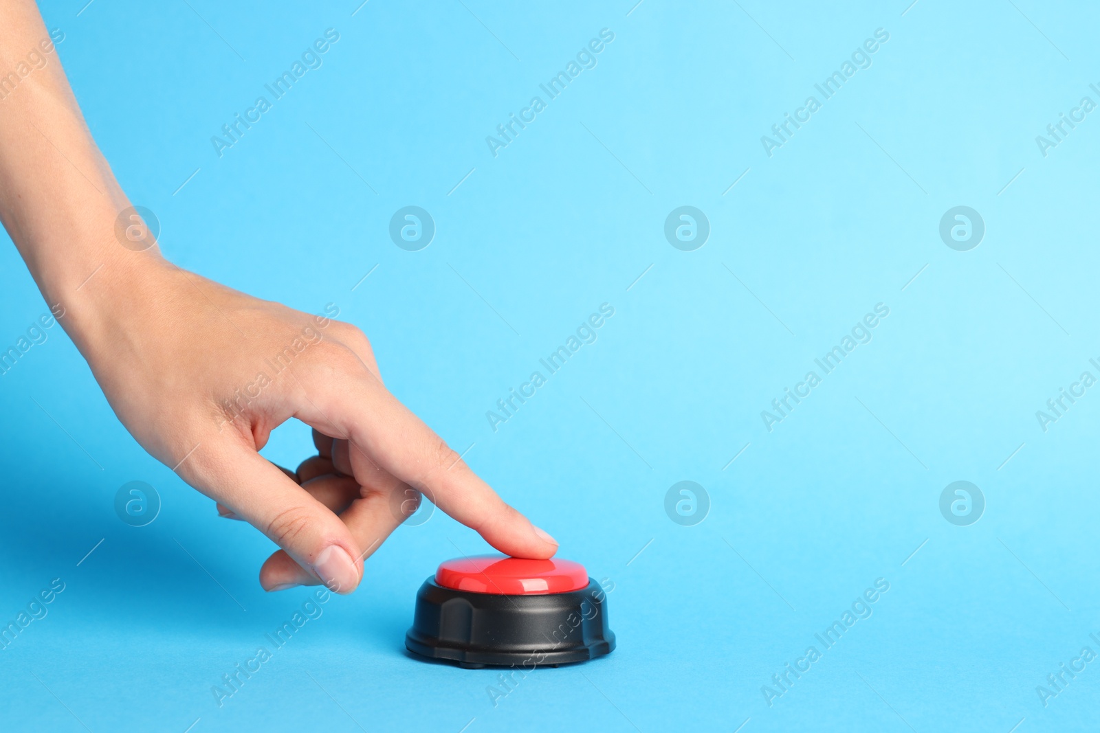 Photo of Woman pressing red button on light blue background, closeup. Space for text
