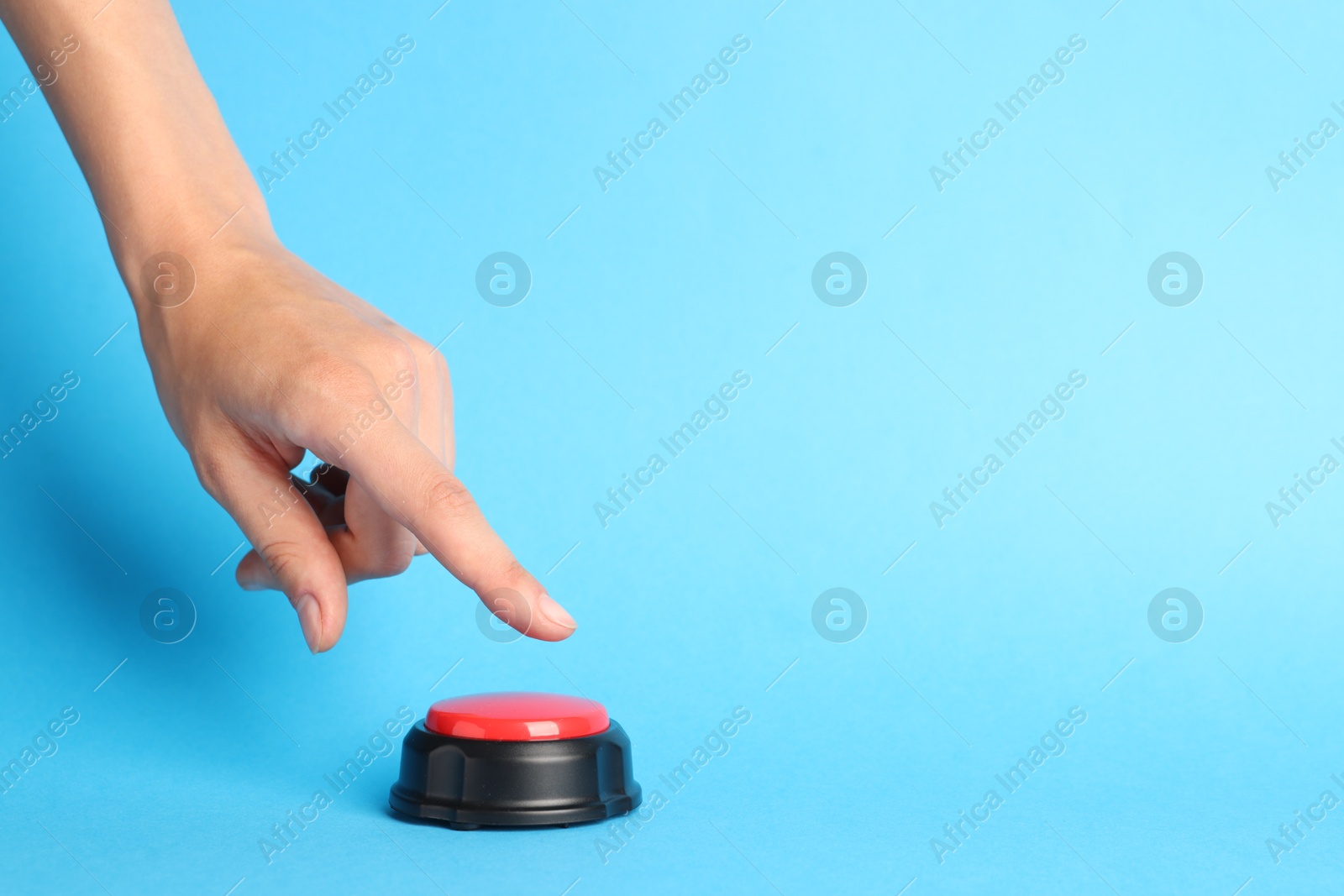Photo of Woman pressing red button on light blue background, closeup. Space for text