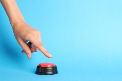 Photo of Woman pressing red button on light blue background, closeup. Space for text