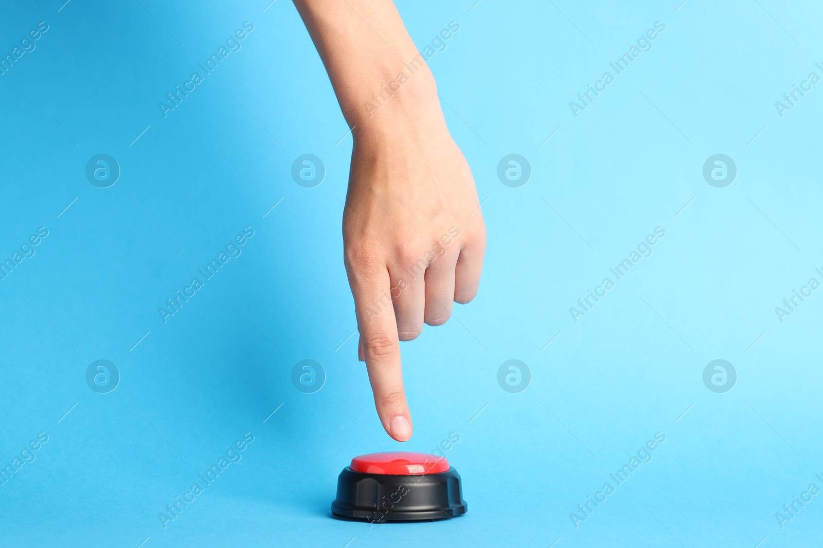 Photo of Woman pressing red button on light blue background, closeup