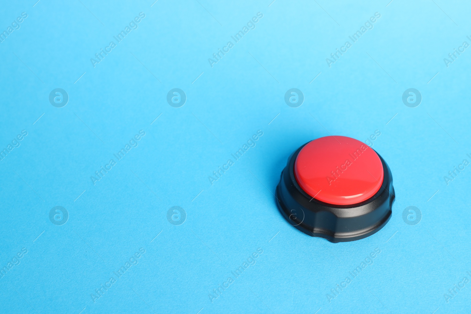 Photo of One red button on light blue background, space for text