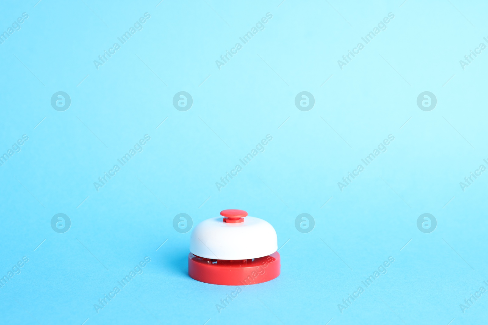 Photo of One red button on light blue background, space for text