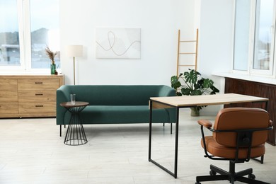 Photo of Stylish living room with sofa, houseplant and workplace. Interior design