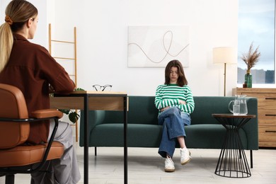 Photo of Professional psychologist working with teenage girl in office