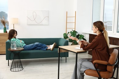 Photo of Professional psychologist working with teenage girl in office