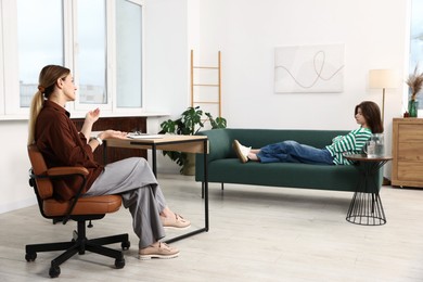 Photo of Professional psychologist working with teenage girl in office