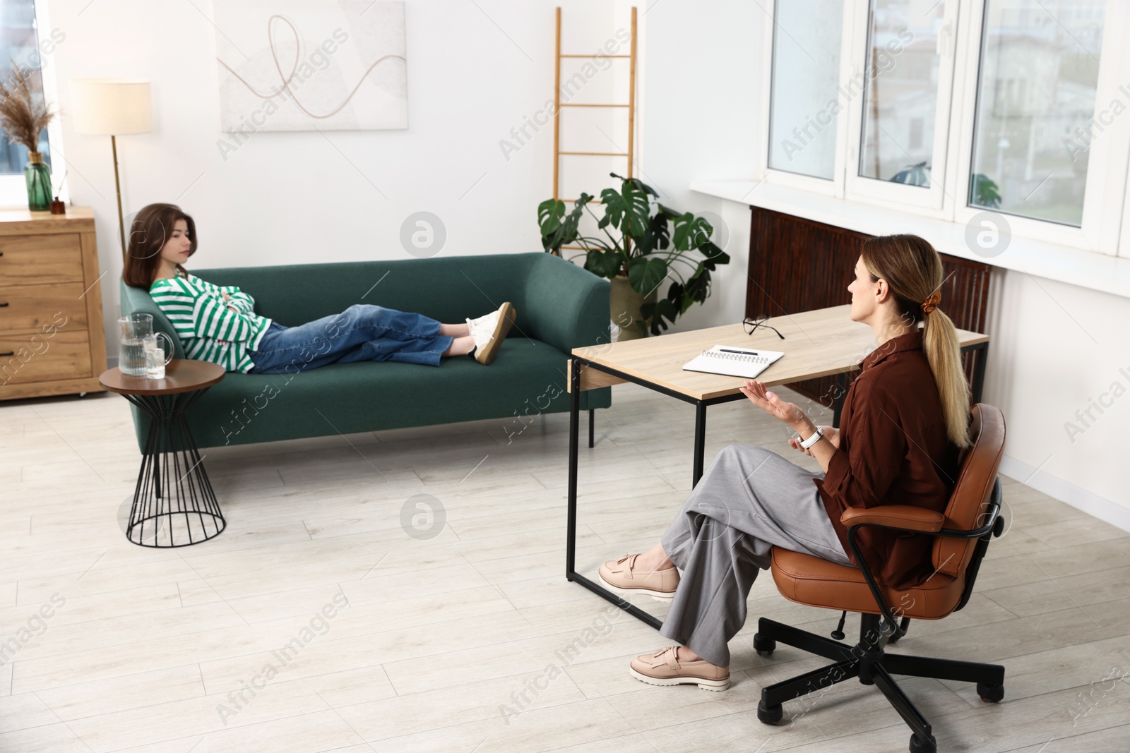 Photo of Professional psychologist working with teenage girl in office