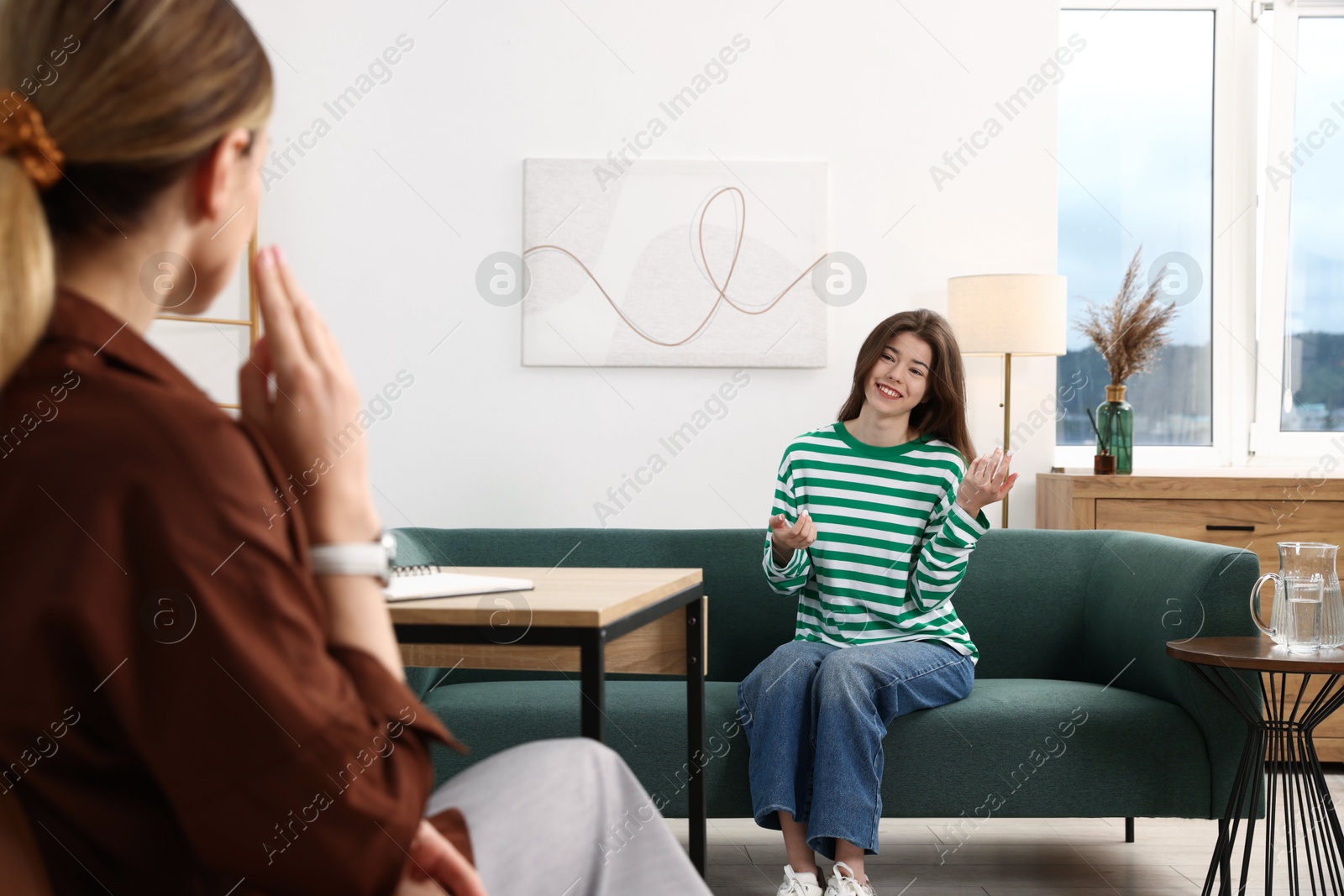 Photo of Professional psychologist working with teenage girl in office, selective focus