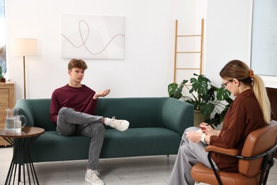 Photo of Professional psychologist working with teenage boy in office