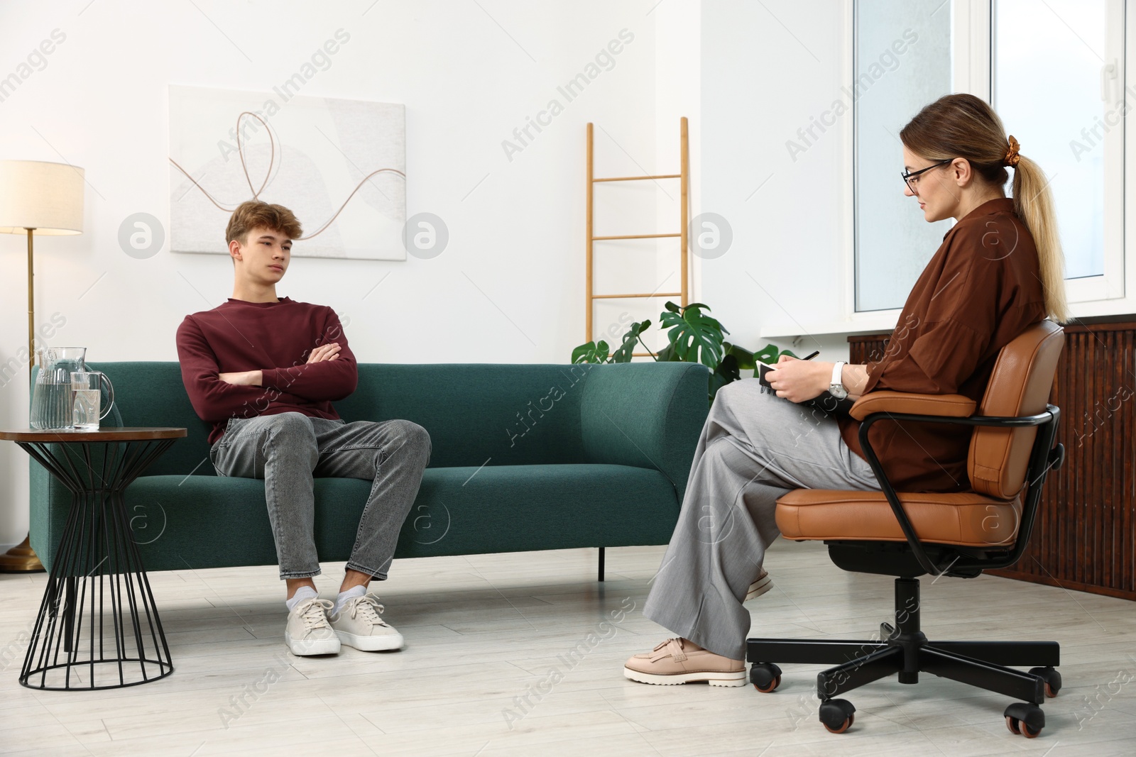 Photo of Professional psychologist working with teenage boy in office