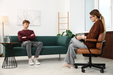 Photo of Professional psychologist working with teenage boy in office