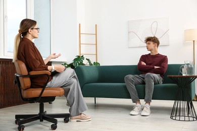 Photo of Professional psychologist working with teenage boy in office