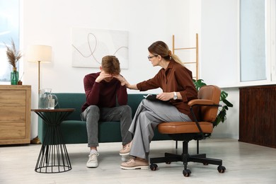 Photo of Professional psychologist working with teenage boy in office