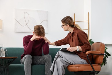 Photo of Professional psychologist working with teenage boy in office