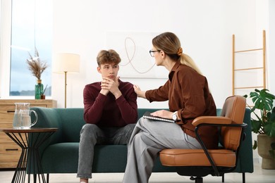 Photo of Professional psychologist working with teenage boy in office