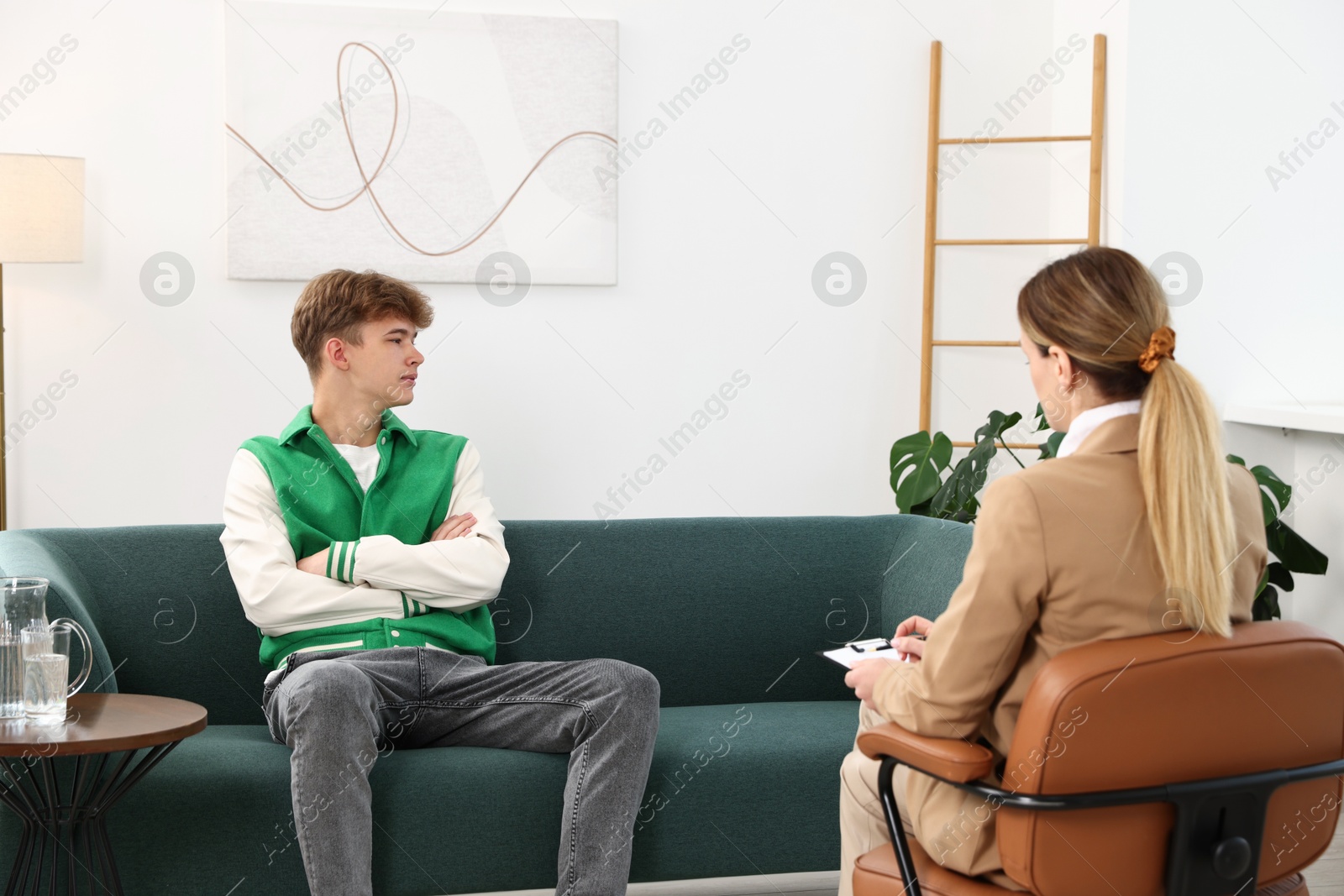 Photo of Professional psychologist working with teenage boy in office